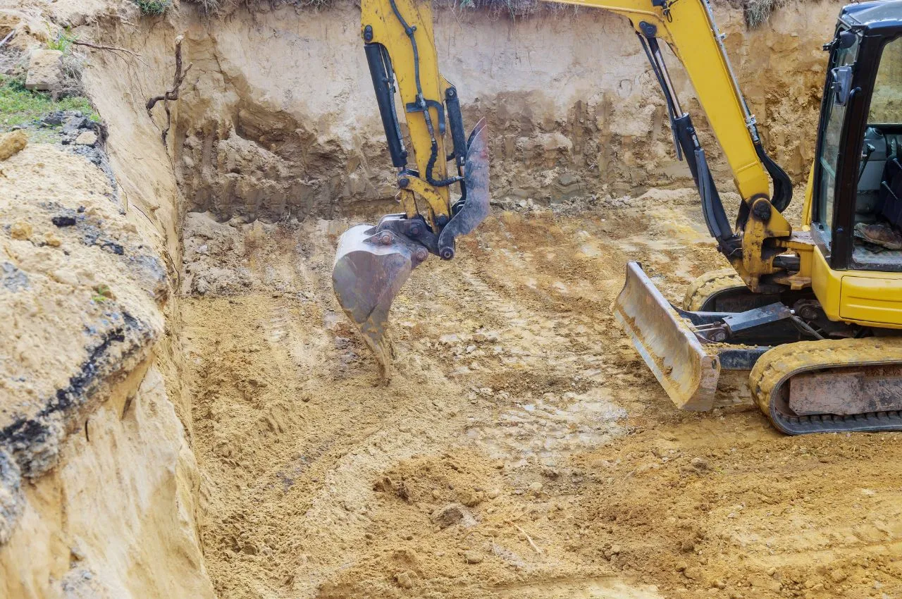 Terrassier conduisant une pelle mécanique sur une plateforme en préparation